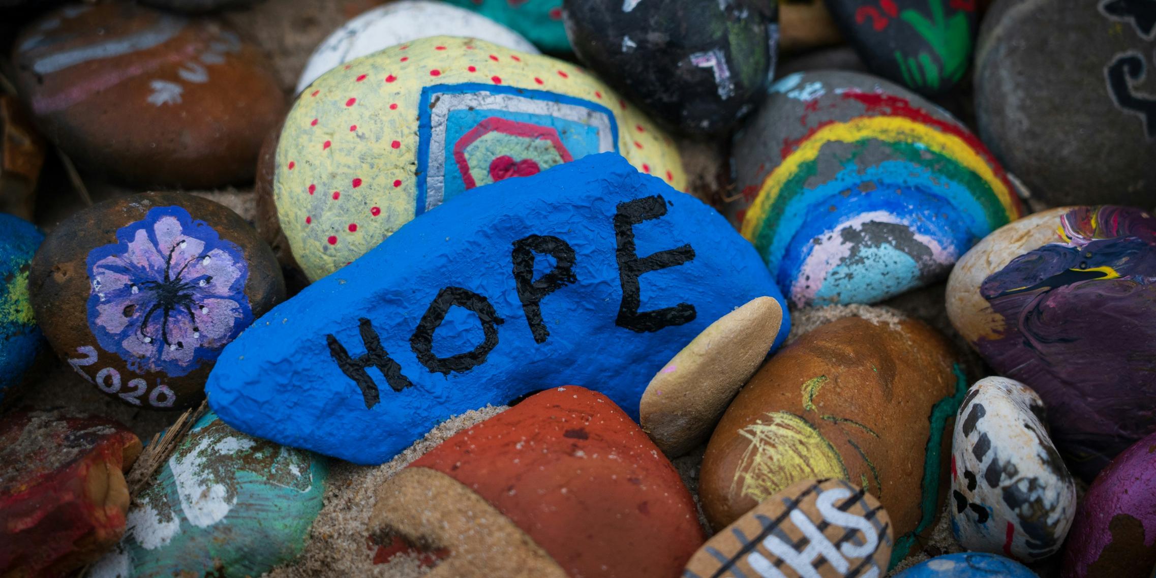 Steine sind bunt bemalt, auf einem steht das Wort Hope