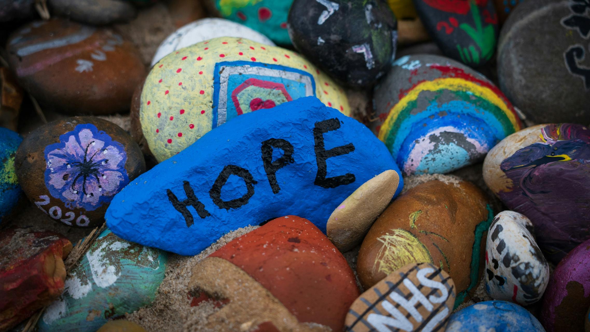 Steine sind bunt bemalt, auf einem steht das Wort Hope