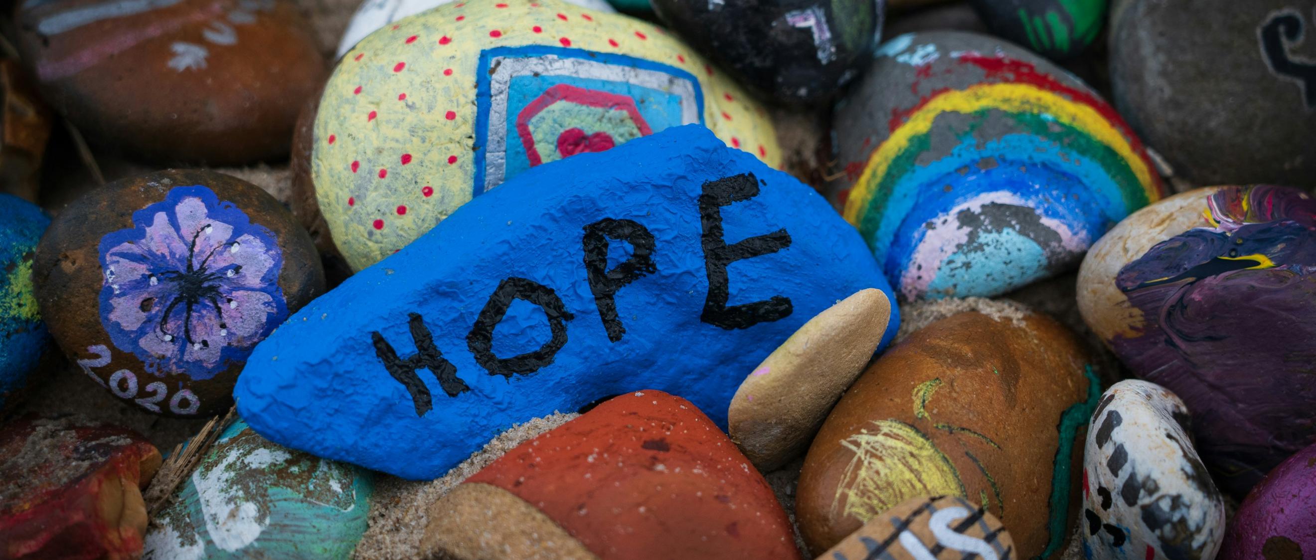 Steine sind bunt bemalt, auf einem steht das Wort Hope