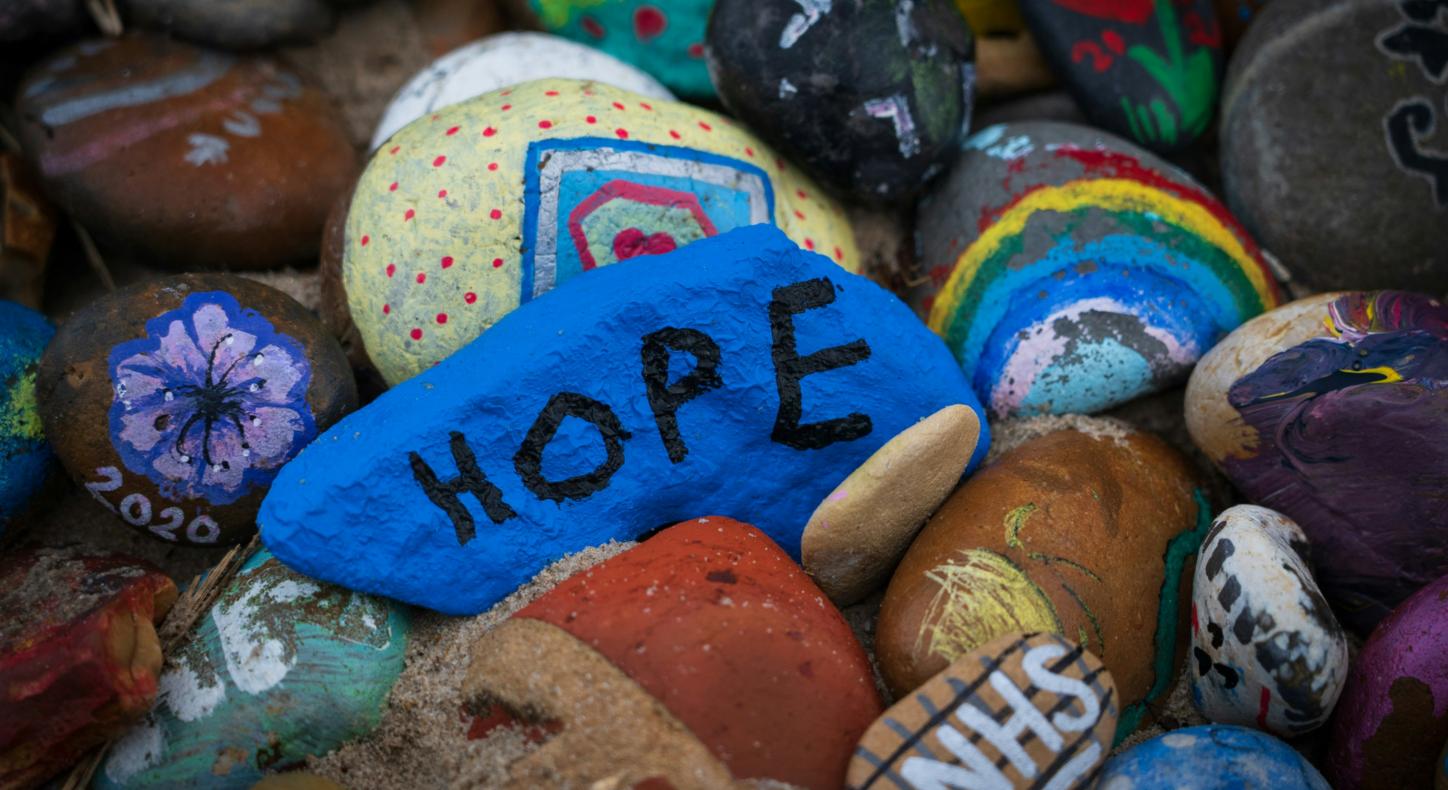 Steine sind bunt bemalt, auf einem steht das Wort Hope
