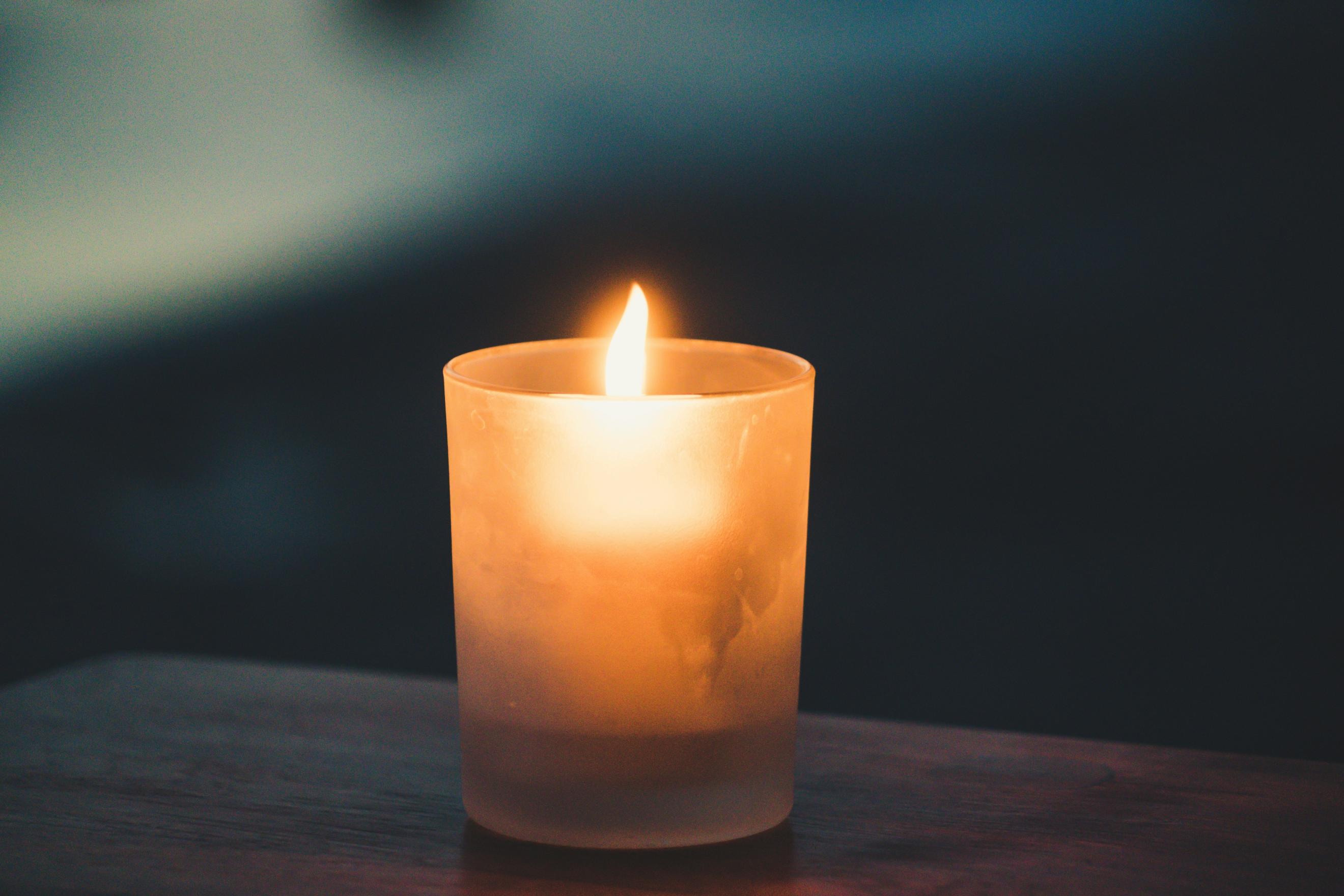 Eine brennende Kerze in einem Glas steht auf einem Tisch (c) Paolo Nicolello / unsplash Eine brennende Kerze in einem Glas steht auf einem Tisch