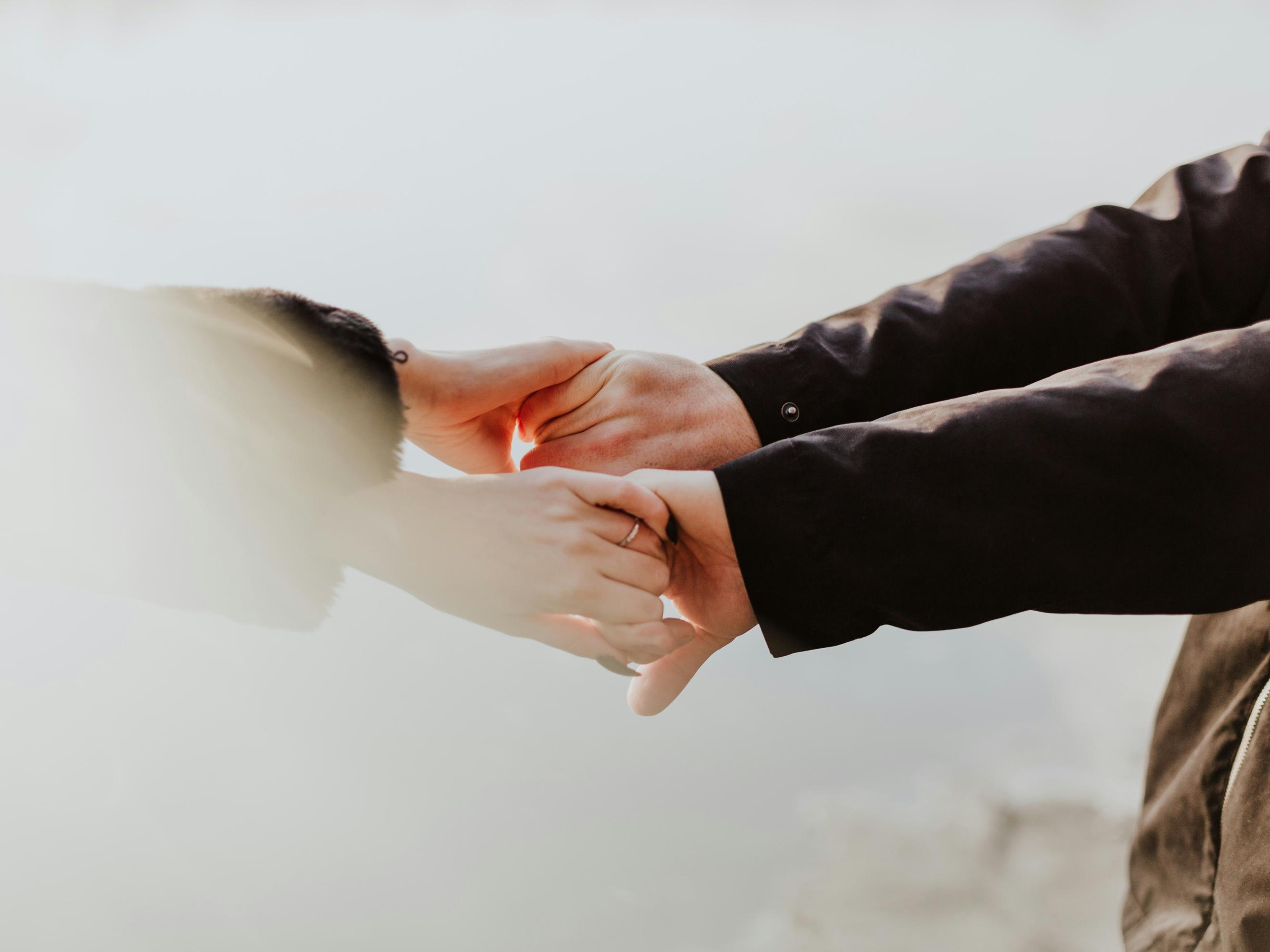 Symbolfoto (c) unsplash.com Zwei paar Hände - männlich und weiblich - halten einander