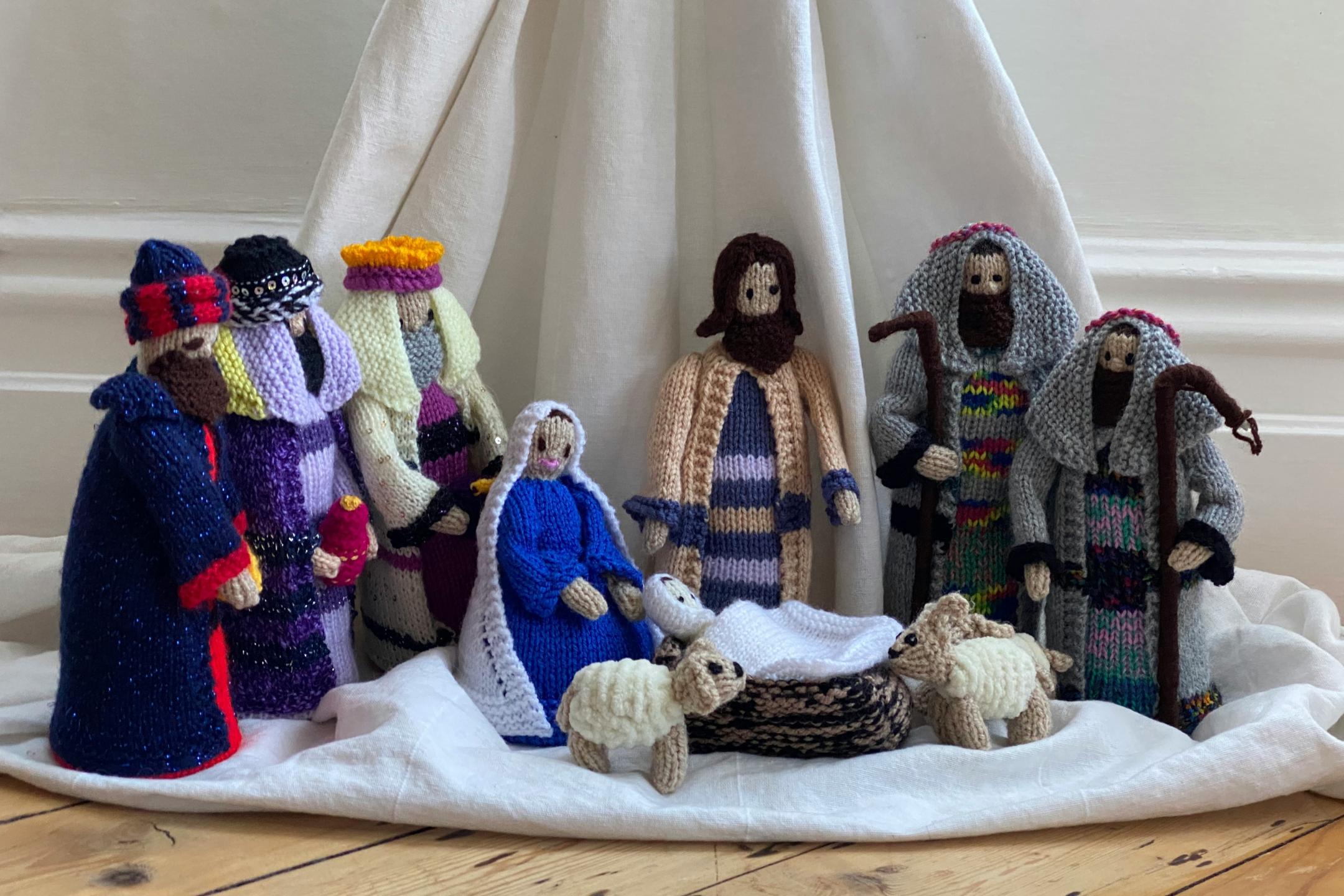 Gehäkelte Figuren stehen vor einem Tuch