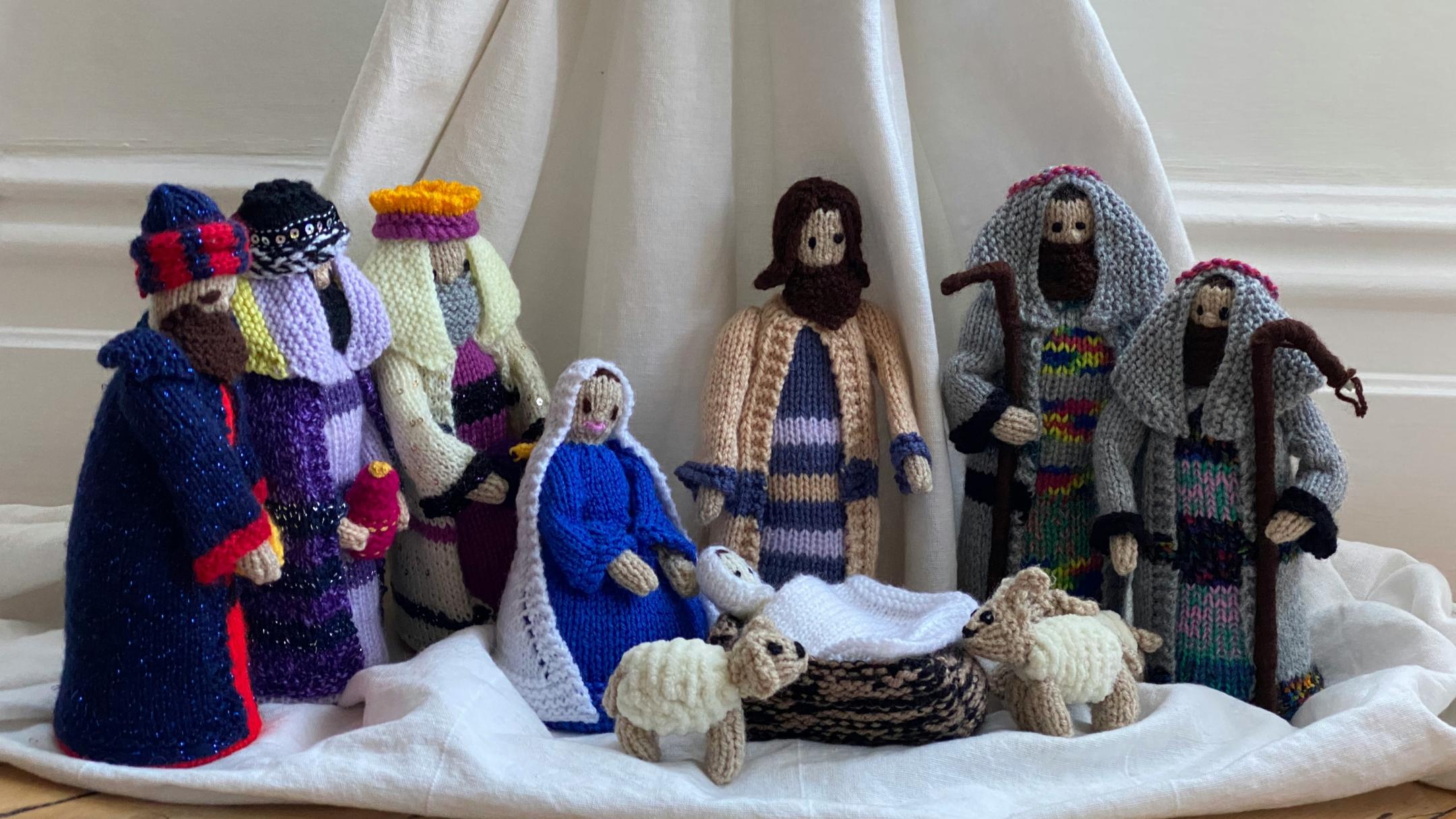 Gehäkelte Figuren stehen vor einem Tuch