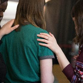 Mehrere Frauen stehen nebeneinander im Gebet und stützen sich