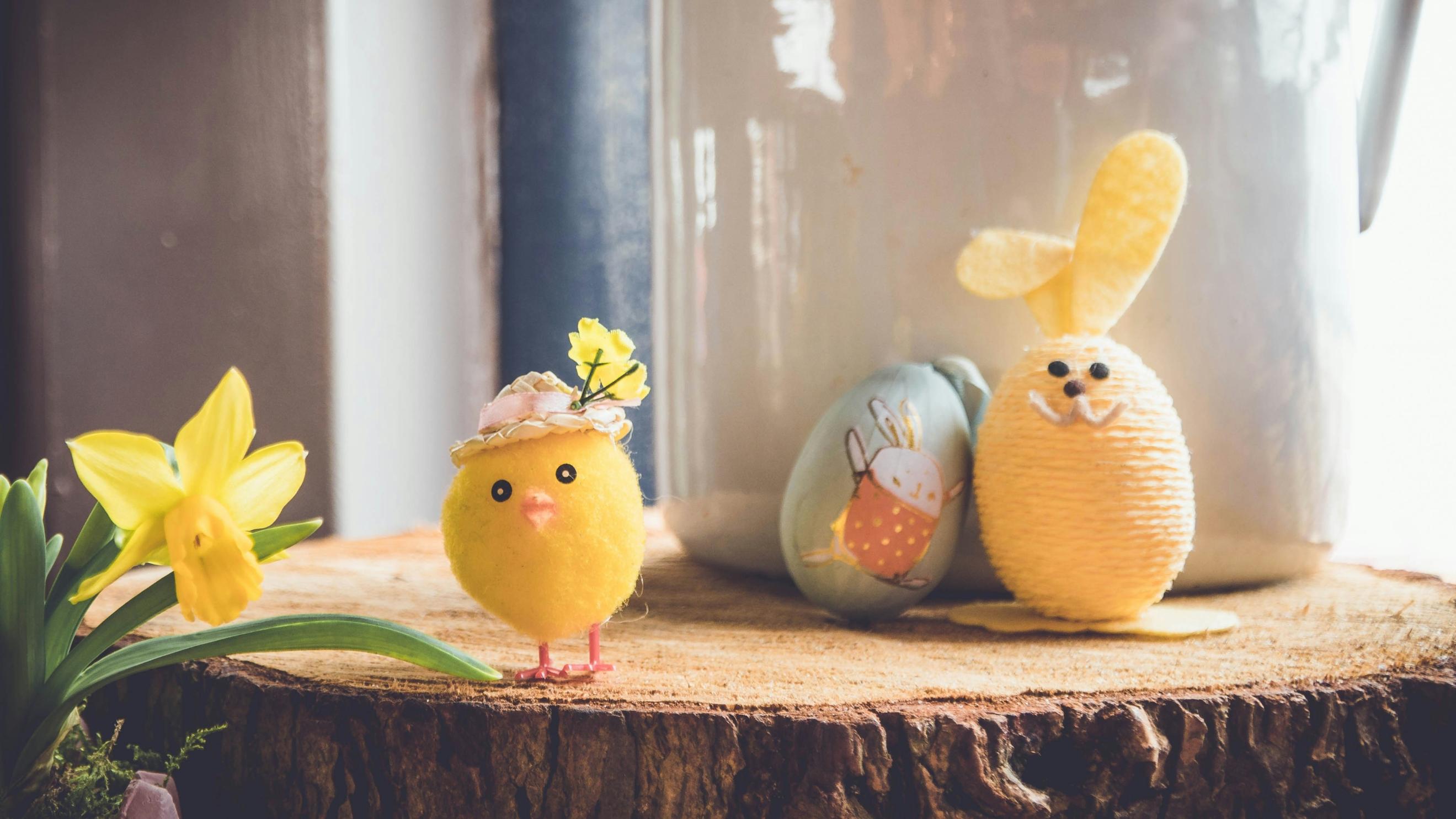 Auf einer Baumscheibe steht ein kleines gebasteltes Küken und ein Osterhase, der aus einem Ei gebastelt wurde