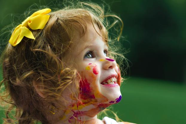 Ein Kind ist mit Farbe beschmiert und lächelt