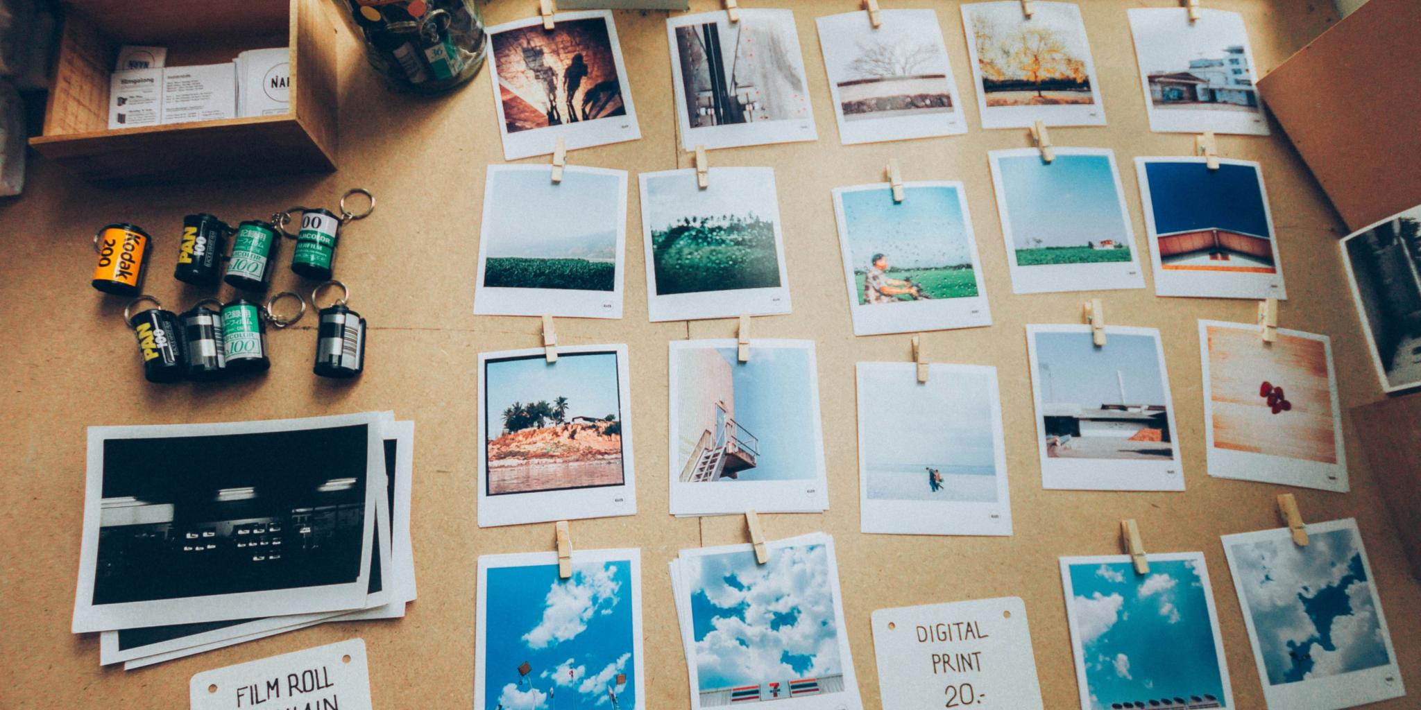 Bunte Fotos liegen auf einem Schreibtisch neben Filmrollen