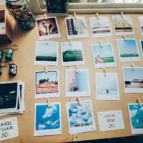 Bunte Fotos liegen auf einem Schreibtisch neben Filmrollen