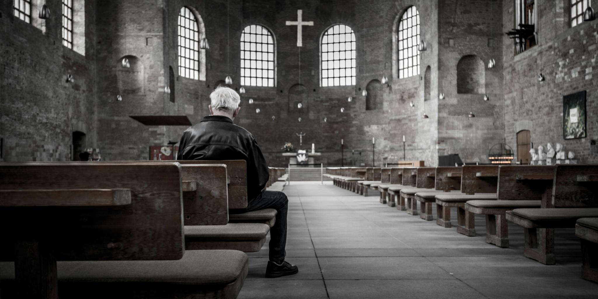 Ein Mann sitzt in einer Kircher auf einer Kirchenbank. Der Mann ist nur von hinten zu sehen. Das Bild ist schwarz weiß (c) Stefan Kunze / unsplash Ein Mann sitzt in einer Kircher auf einer Kirchenbank. Der Mann ist nur von hinten zu sehen. Das Bild ist schwarz weiß