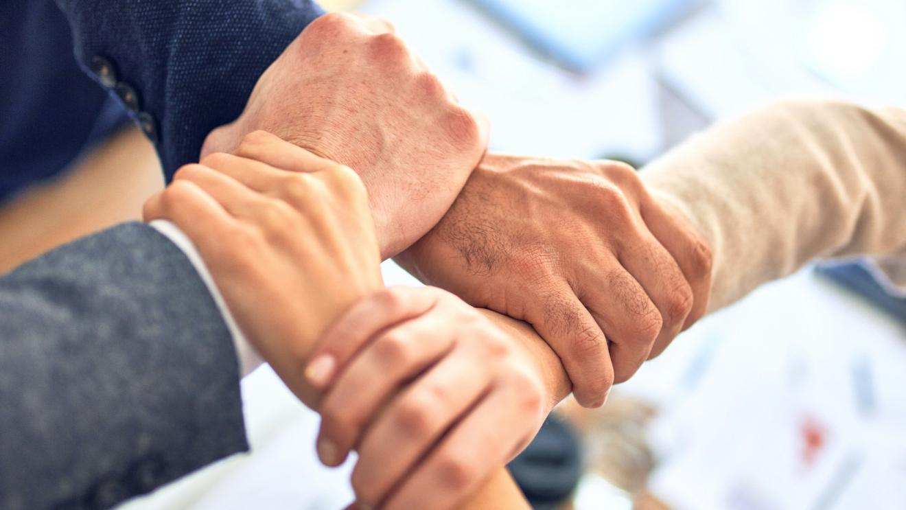 vier Hände greifen ein anderes Handgelenk, so dass eine stabile Fläche entsteht