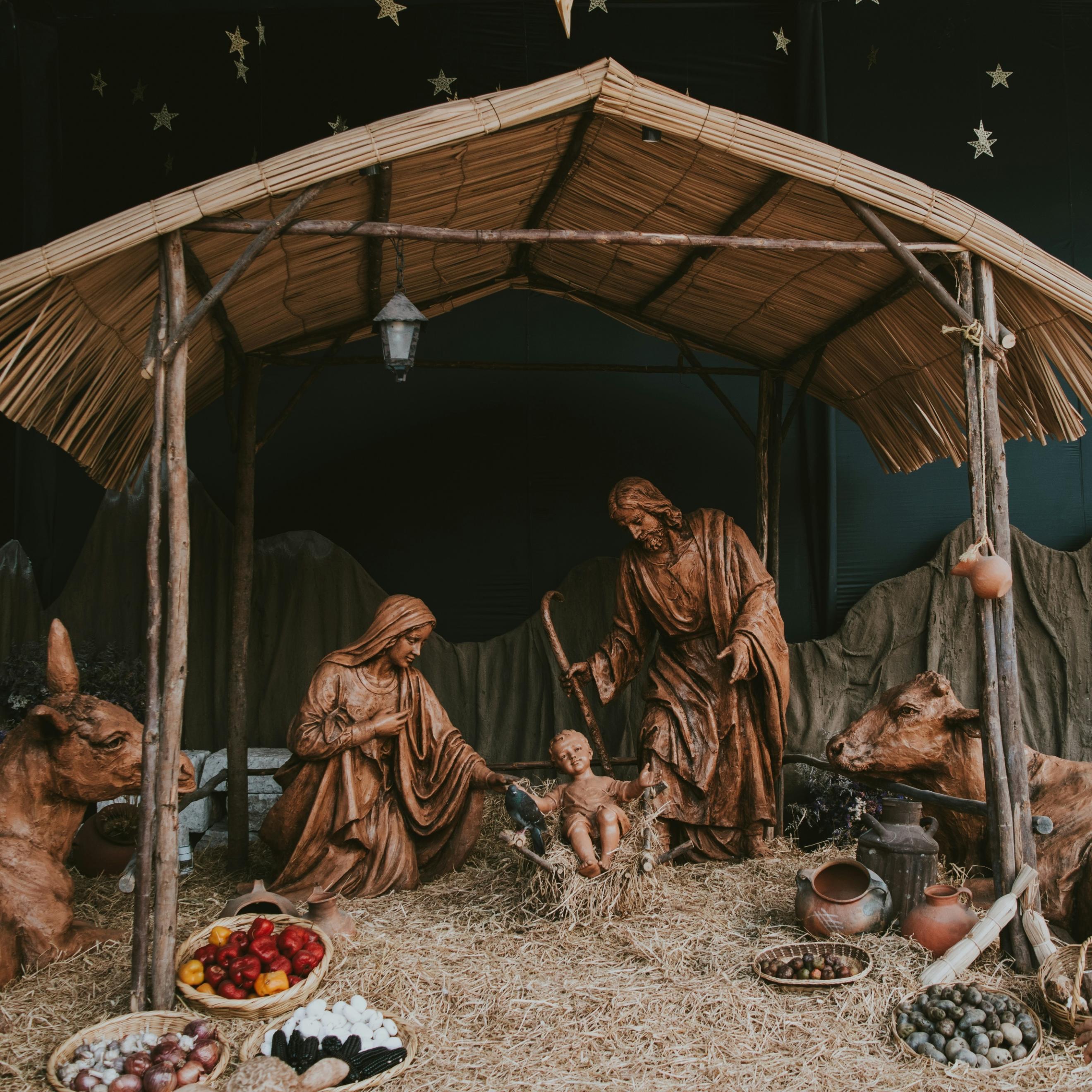 Eine Hütte aus Holz in der Josef und Maria um das Jesuskind stehen. Die Hütte ist beleuchtet, ebenso wie die Bäume im Hintergrund