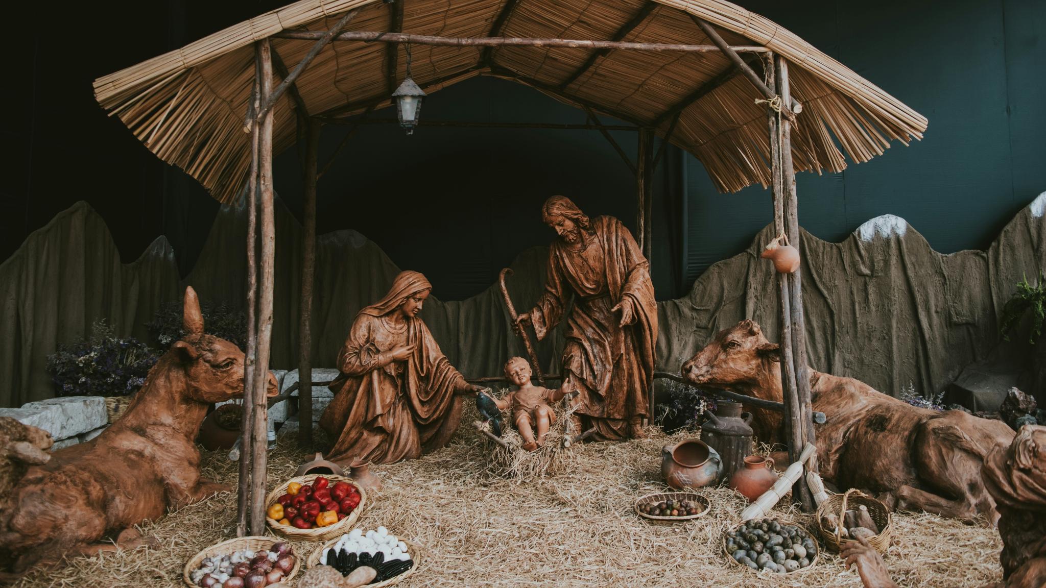 Eine Hütte aus Holz in der Josef und Maria um das Jesuskind stehen. Die Hütte ist beleuchtet, ebenso wie die Bäume im Hintergrund