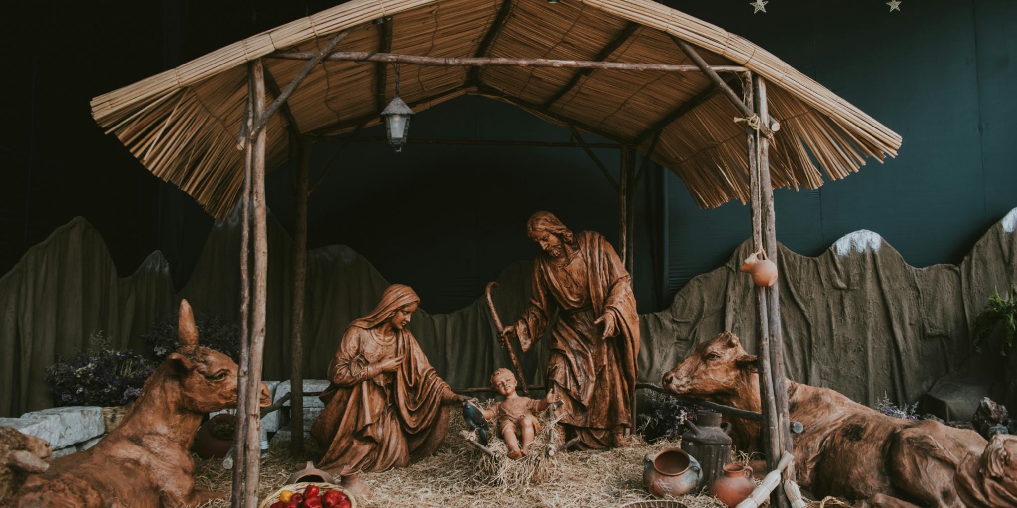 Eine Hütte aus Holz in der Josef und Maria um das Jesuskind stehen. Die Hütte ist beleuchtet, ebenso wie die Bäume im Hintergrund