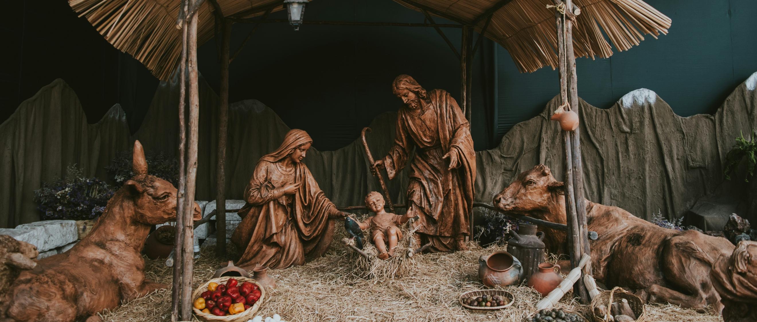 Eine Hütte aus Holz in der Josef und Maria um das Jesuskind stehen. Die Hütte ist beleuchtet, ebenso wie die Bäume im Hintergrund