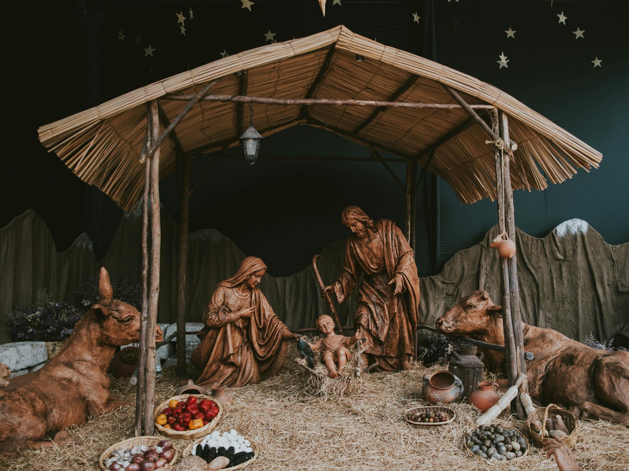 Eine Hütte aus Holz in der Josef und Maria um das Jesuskind stehen. Die Hütte ist beleuchtet, ebenso wie die Bäume im Hintergrund