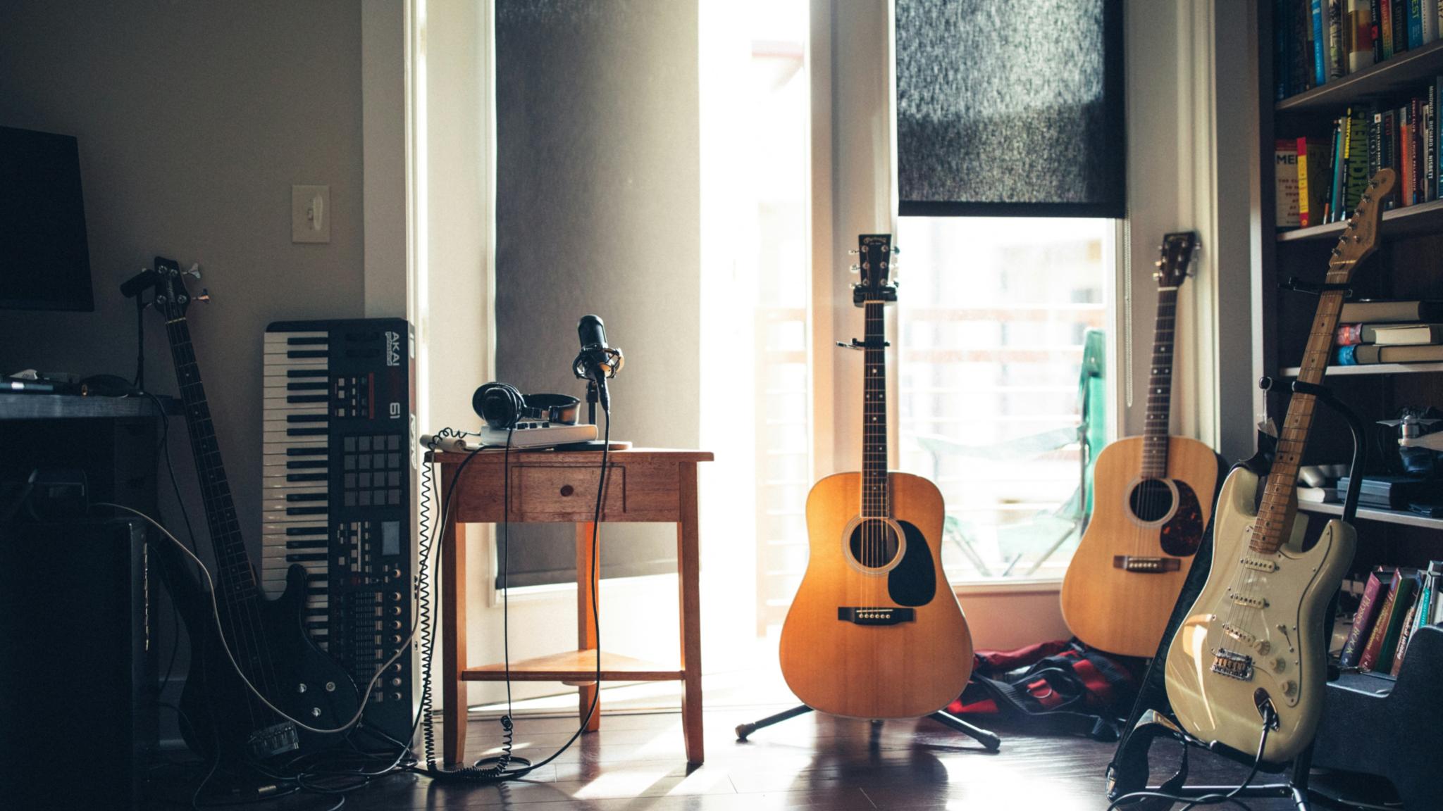 In einem Raum mit einem großen Fenster stehen Gitarren und ein Keyboard