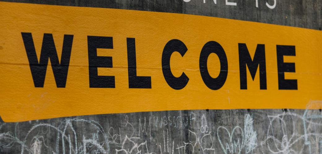 Auf einer Wand steht der Text 'Everyone is welcome'. Darunter sind viele kleine Kreidezeichnungen