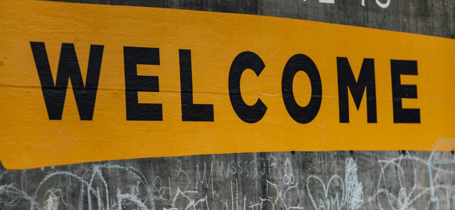 Auf einer Wand steht der Text 'Everyone is welcome'. Darunter sind viele kleine Kreidezeichnungen