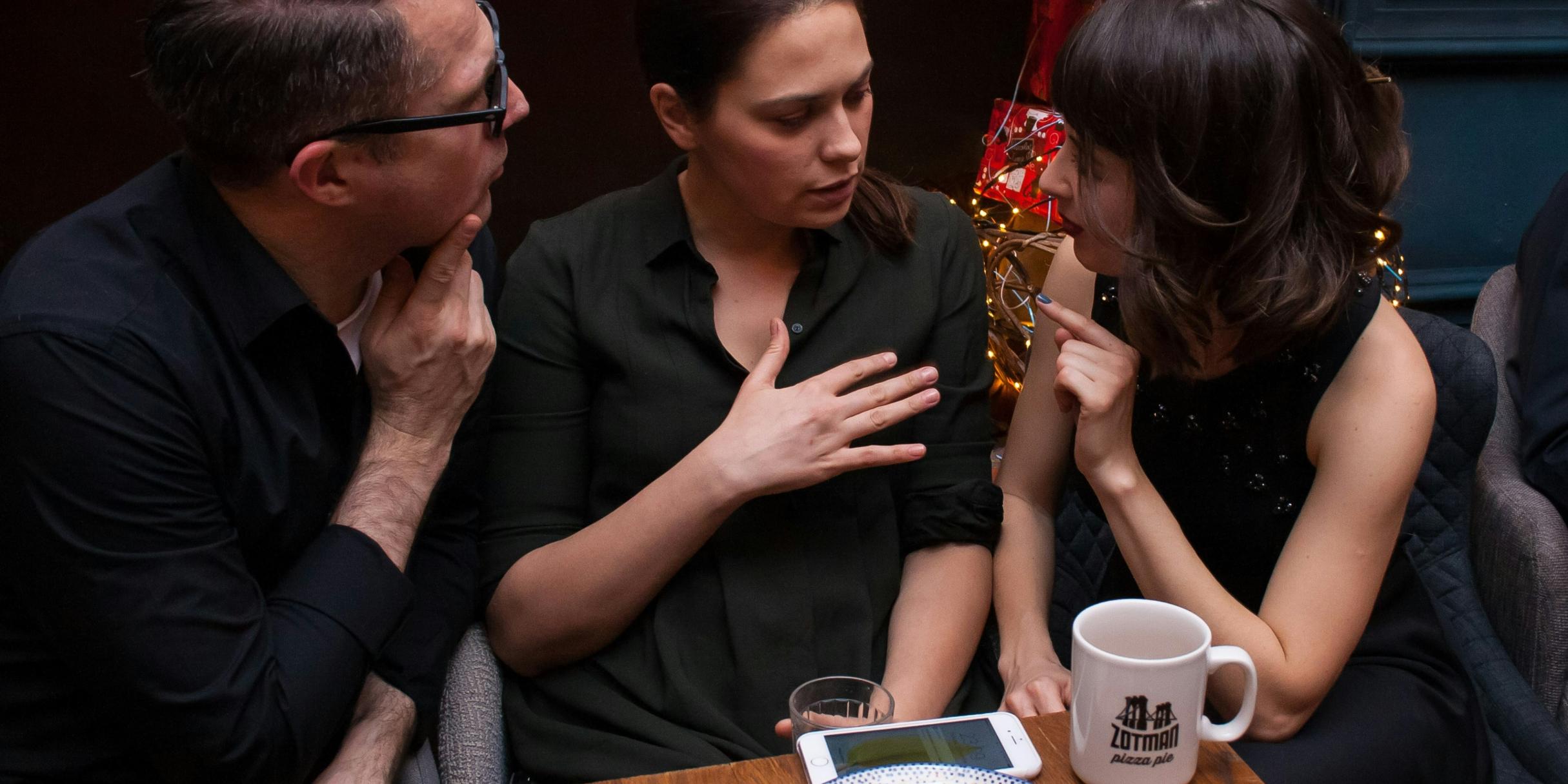 Drei Menschen sitzen mit Kaffee und Kuchen am Tisch und unterhalten sich