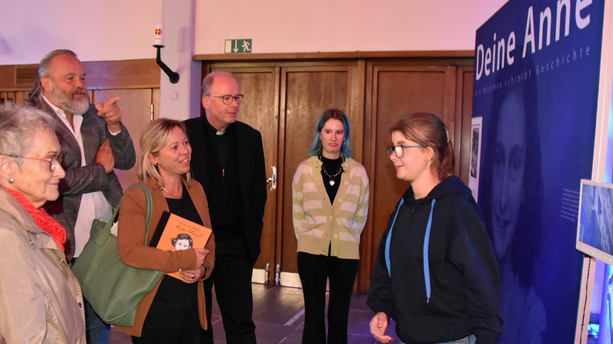 Eine Jugendliche führt Besucher - darunter Staatssekretärin Jessica Heide und Bischof Ackermann - durch die Ausstellung.