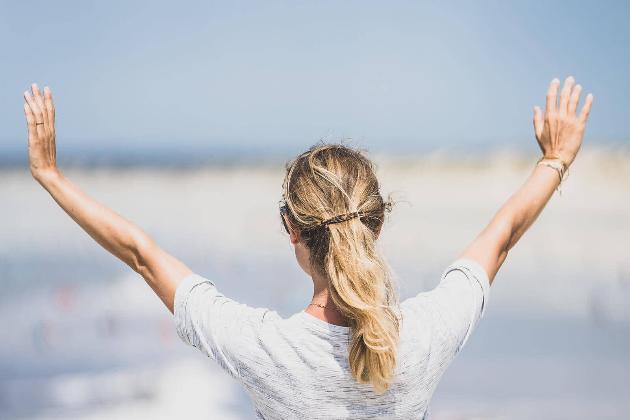 Frau hebt die Hände über den Wolken