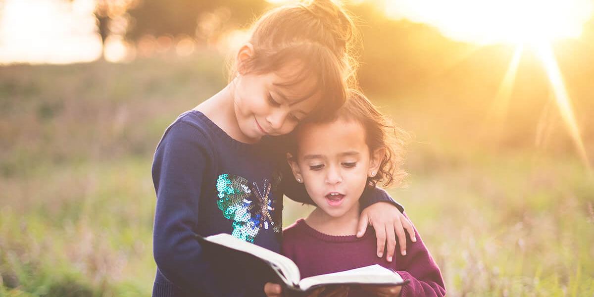 Zwei Kinder lesen ein Buch im Sonnenlicht
