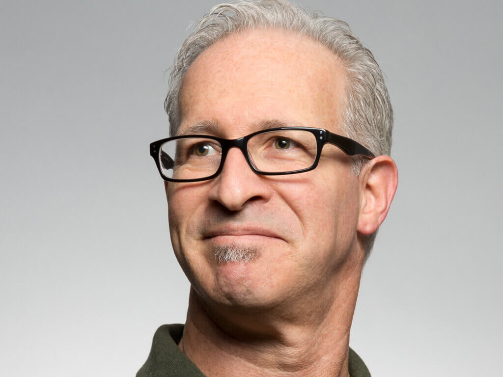 Portrait eines Mannes mit Brille vor hellem Hintergrund